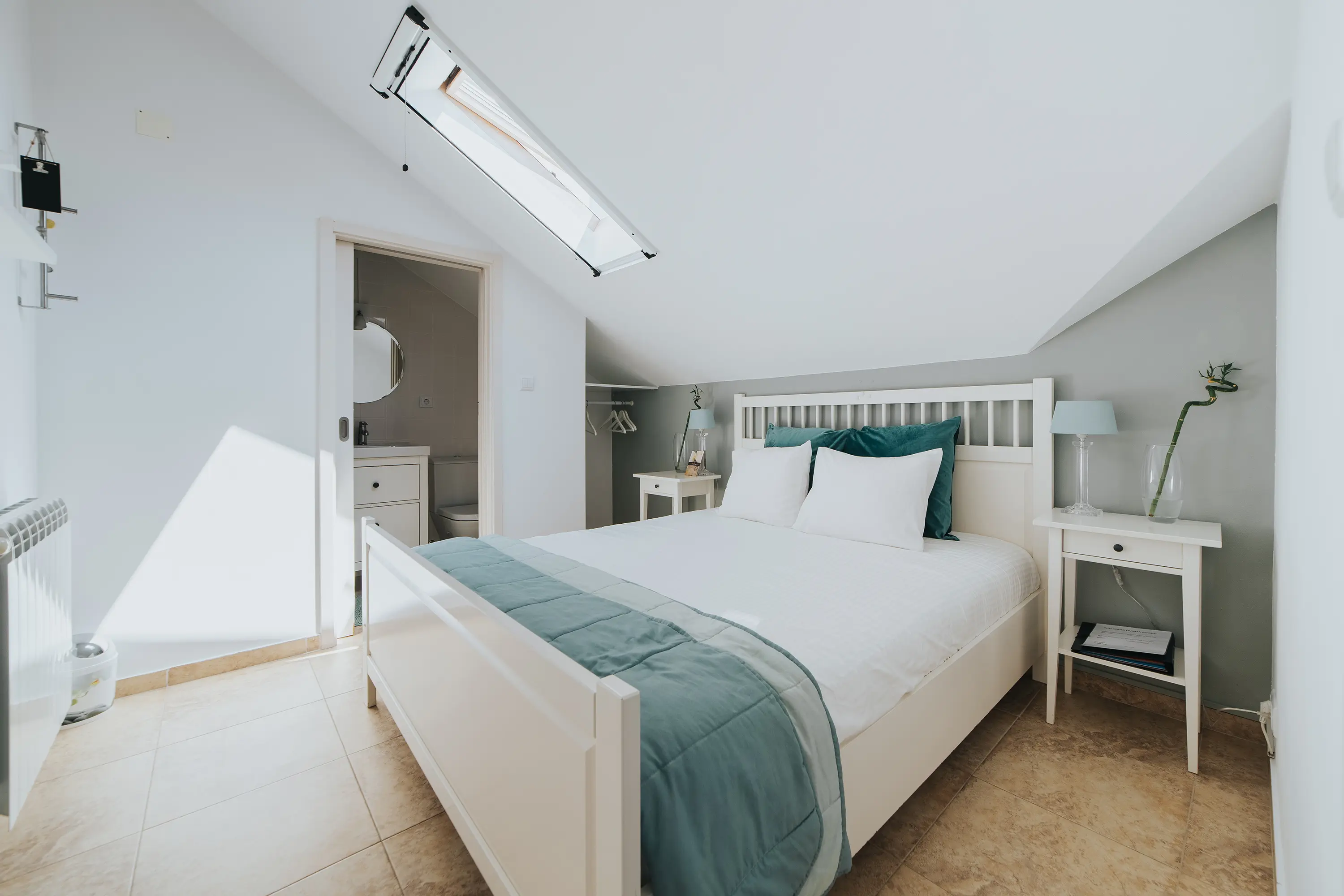 Interior de quarto em alojamento local com cama branca e detalhes em azul
