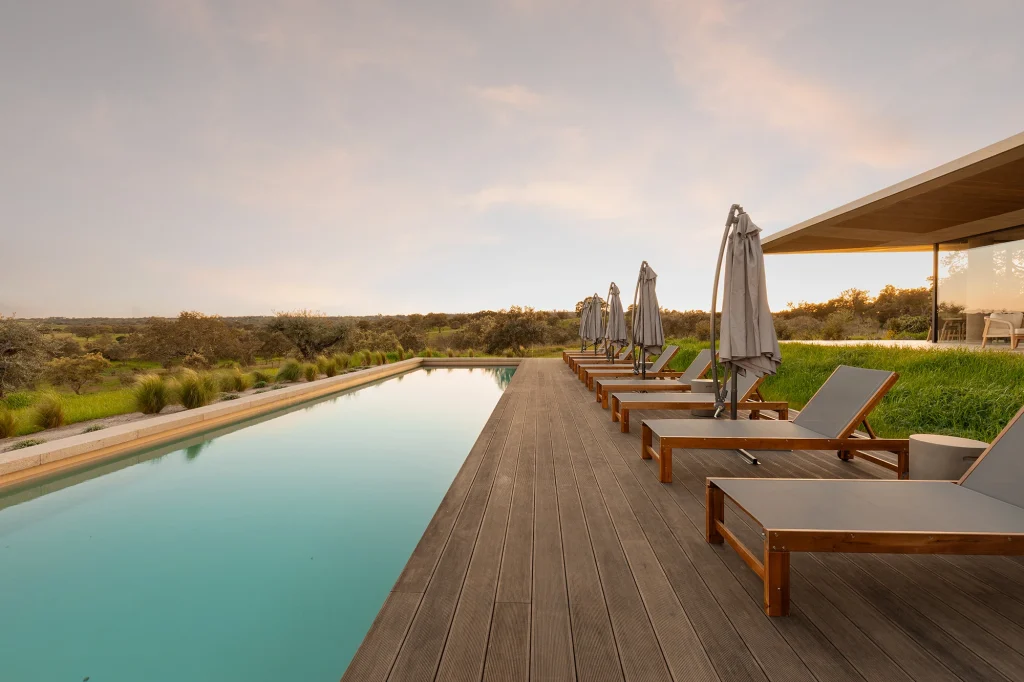 Deck de madeira com piscina ao pôr do sol numa moradia no Porto.