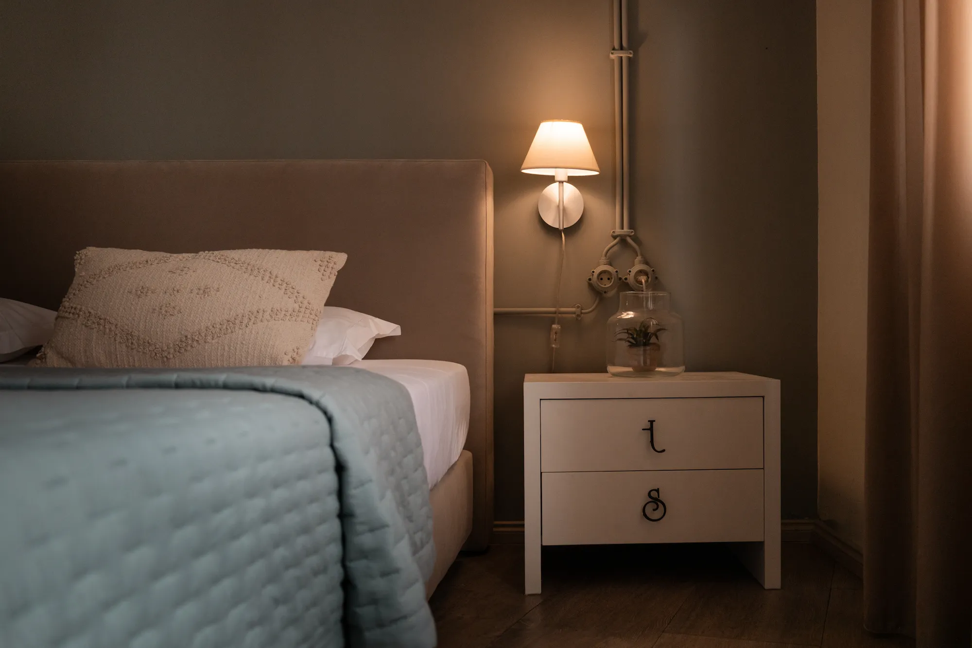 Mesa de cabeceira com iluminação quente em quarto de hotel